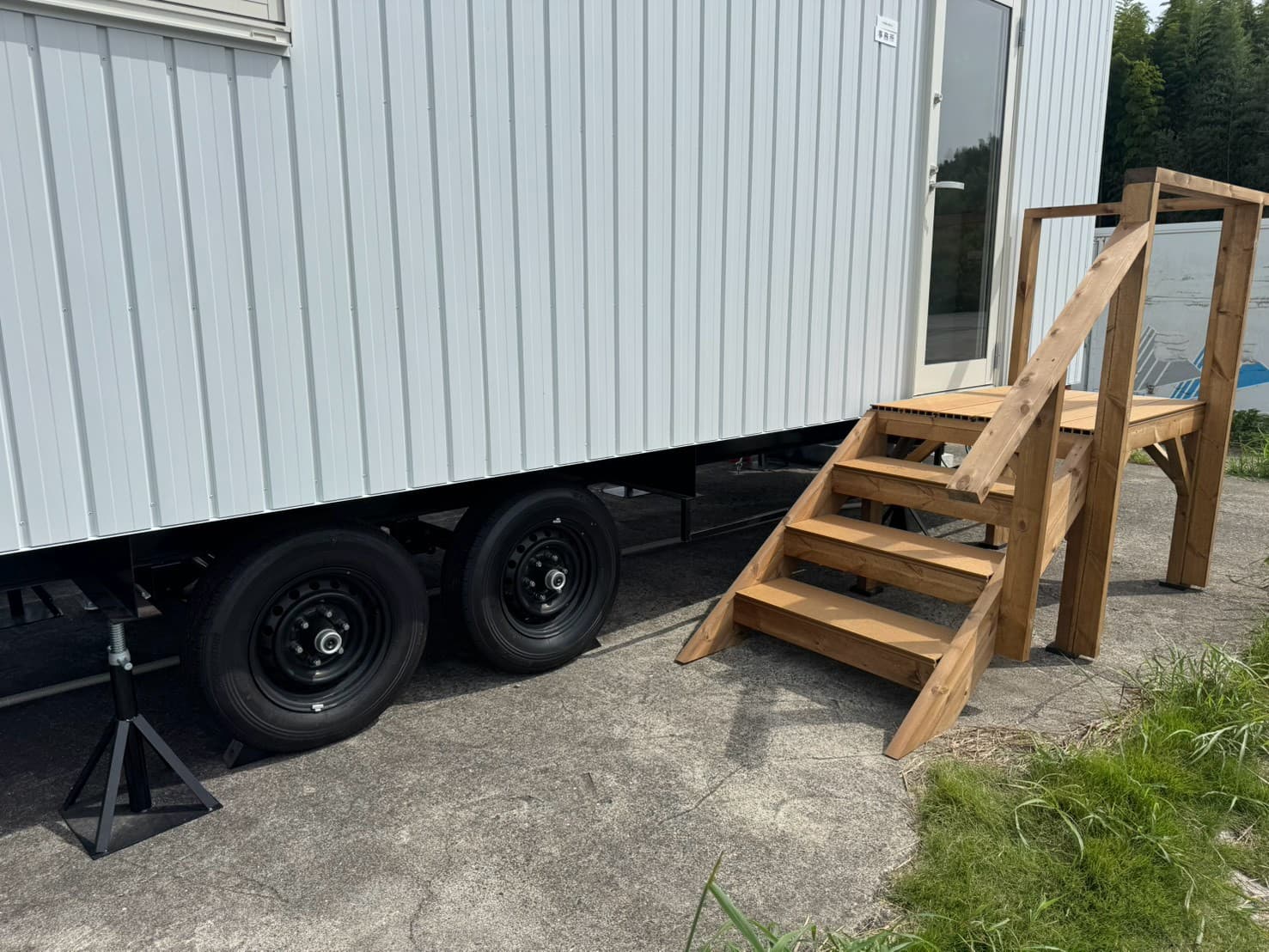 ホワイトの金属外装と木製ステップを備えたトレーラーハウス